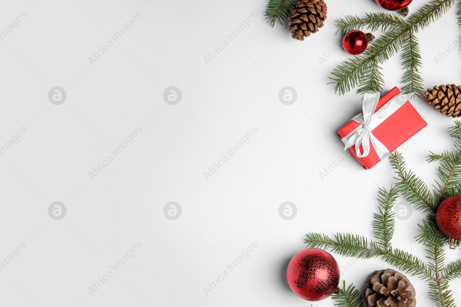 Photo of Christmas greeting card with space for text. Flat lay composition of fir tree branches and festive decor on white background