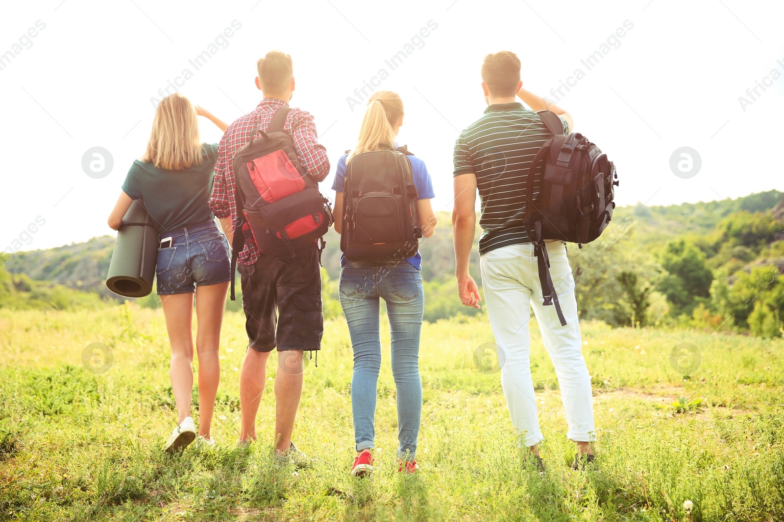 Photo of Group of young people with backpacks in wilderness. Camping season