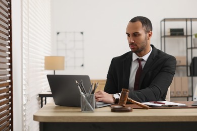 Photo of Serious lawyer working with laptop at table in office