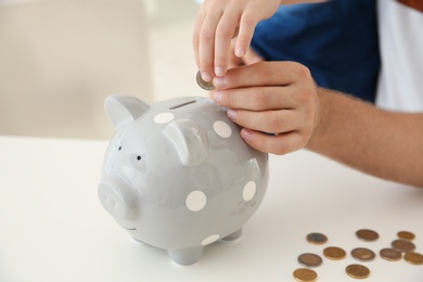 Photo of Father and son putting coin into piggy bank on blurred background, closeup