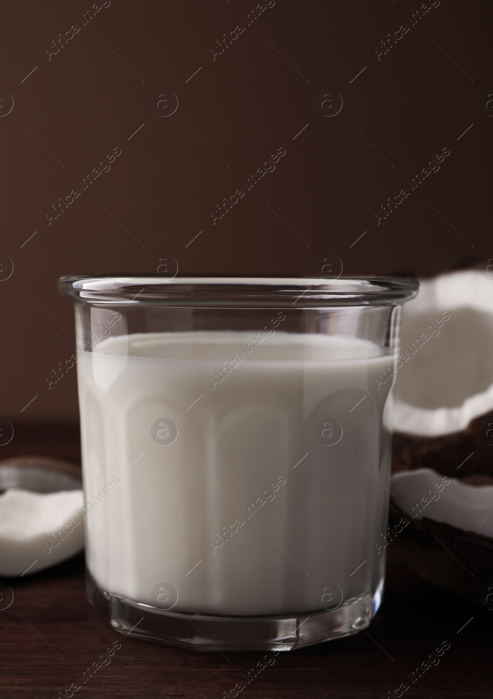 Photo of Glass of delicious vegan milk and coconut pieces on wooden table