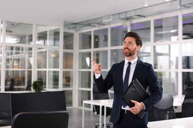 Happy real estate agent with leather portfolio in office