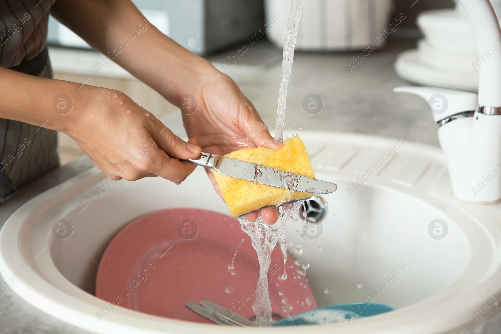 Photo of Woman washing dishes in kitchen sink, closeup view. Cleaning chores