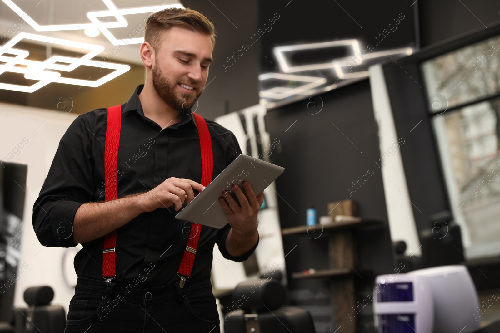 Photo of Young business owner with tablet in barber shop