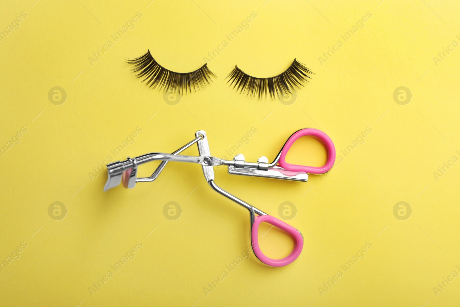 Photo of Flat lay composition of curler and false eyelashes on color background