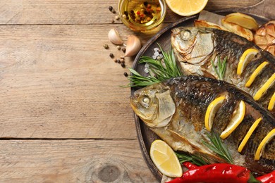 Photo of Tasty homemade roasted crucian carps served on wooden table, flat lay and space for text. River fish