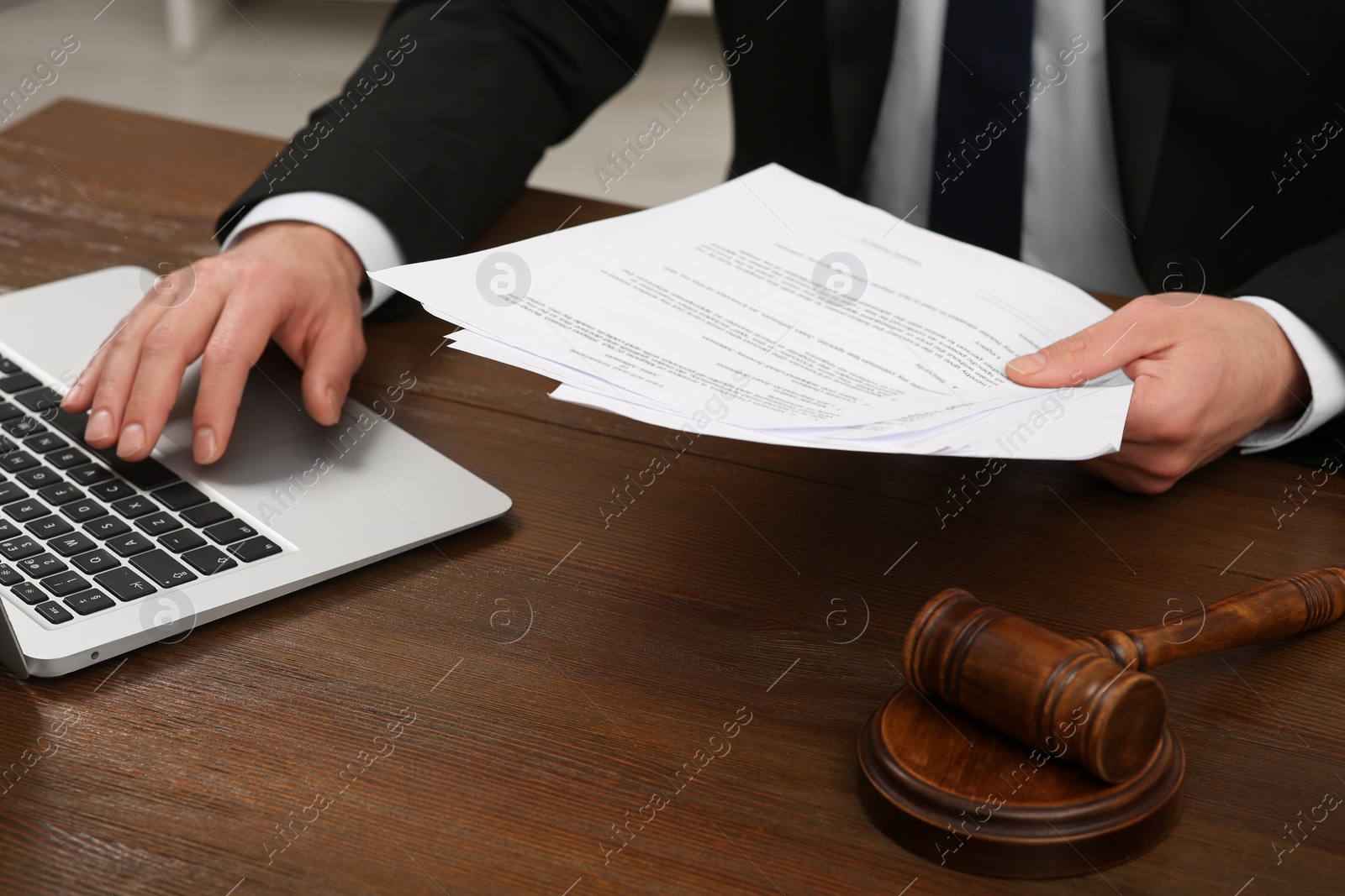 Photo of Law and justice. Lawyer working with documents and laptop at wooden table, closeup