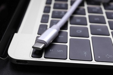 Photo of USB cable with type C connector on laptop keyboard, closeup