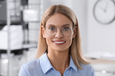 Photo of Portrait of beautiful businesswoman in glasses indoors. Confident lady with blonde hair looking into camera