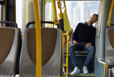 Photo of Tired man sleeping while sitting in public transport