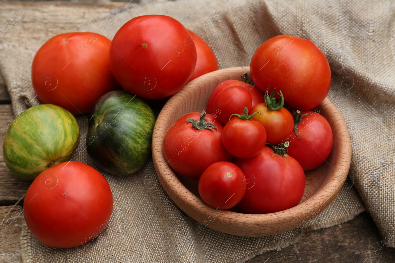 Photo of Many different ripe tomatoes on wooden table