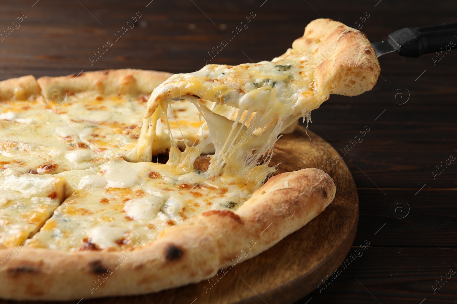 Photo of Taking piece of delicious cheese pizza at wooden table, closeup