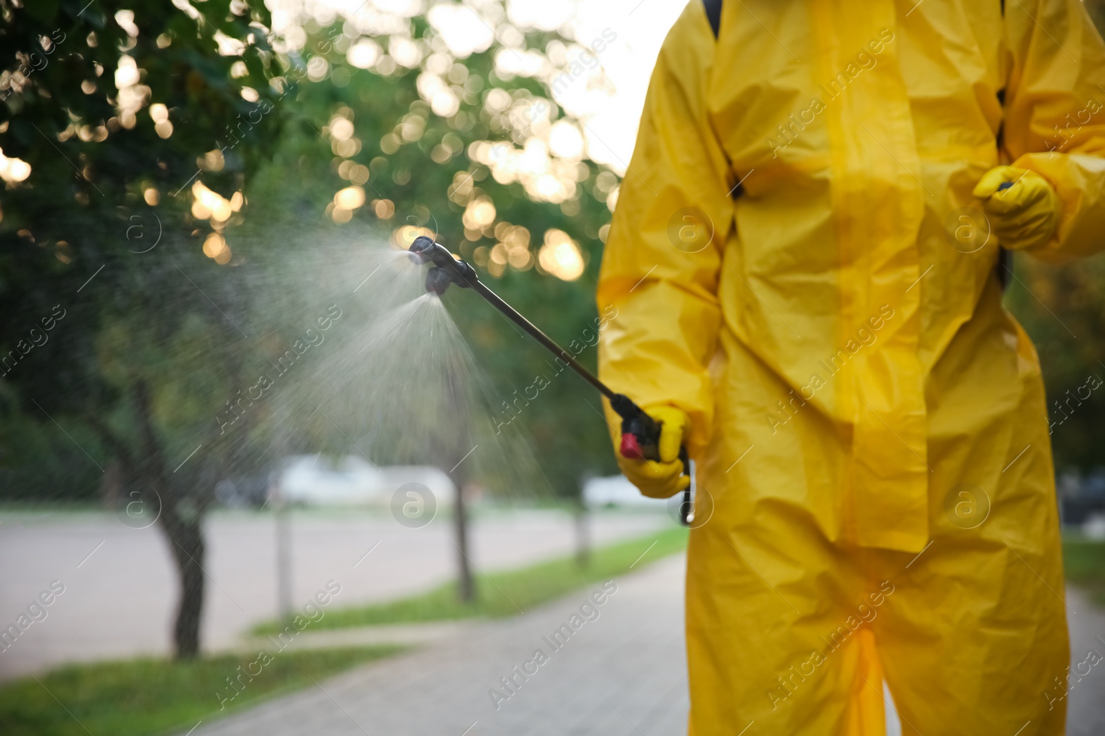 Photo of Person in hazmat suit disinfecting street with sprayer, closeup. Surface treatment during coronavirus pandemic