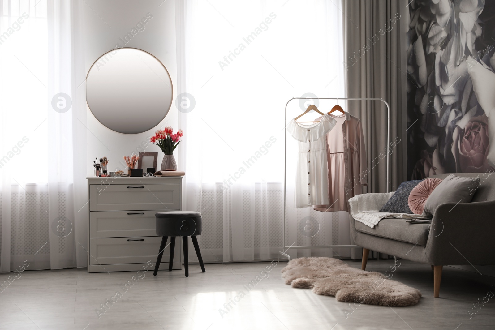 Photo of Stylish room interior with dressing table, mirror, sofa and floral wallpaper
