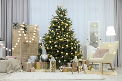 Beautiful Christmas tree, gift boxes and armchair in festive decorated room. Interior design