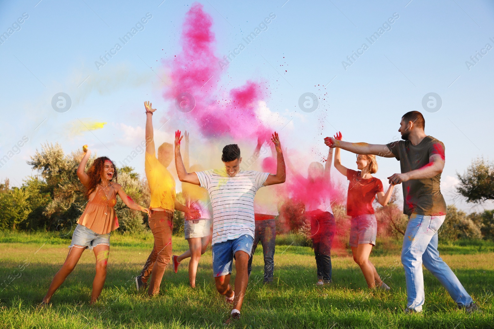 Photo of Happy friends having fun with colorful powder dyes outdoors. Holi festival celebration