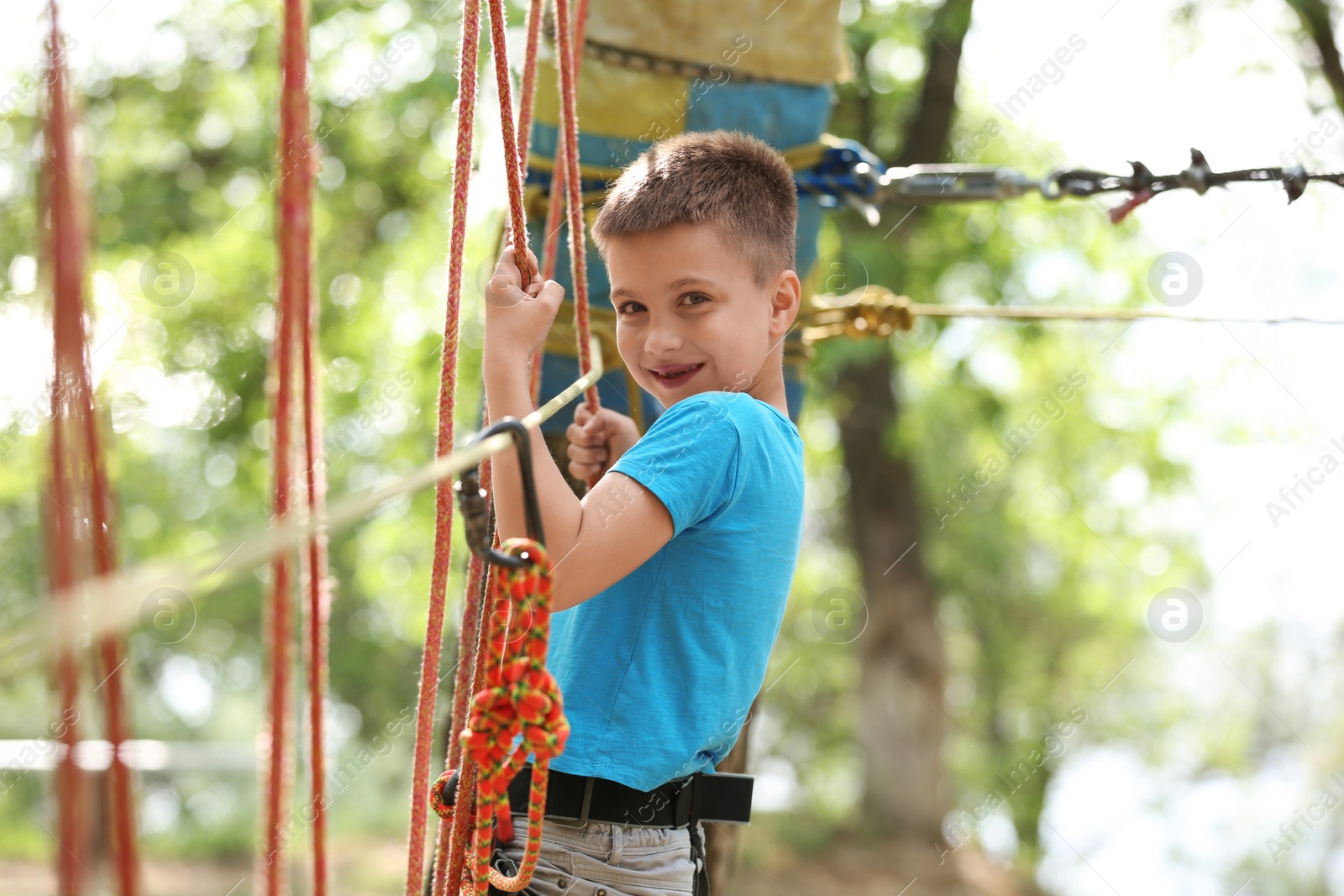 Photo of Little boy climbing in adventure park. Summer camp