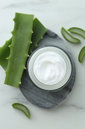 Jar with cream and cut aloe leaves on white marble table, flat lay