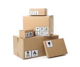 Photo of Cardboard boxes with different packaging symbols on white background. Parcel delivery