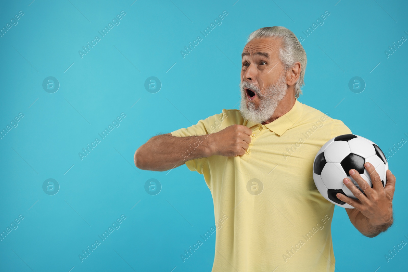 Photo of Emotional senior sports fan with soccer ball on light blue background, space for text