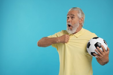 Photo of Emotional senior sports fan with soccer ball on light blue background, space for text