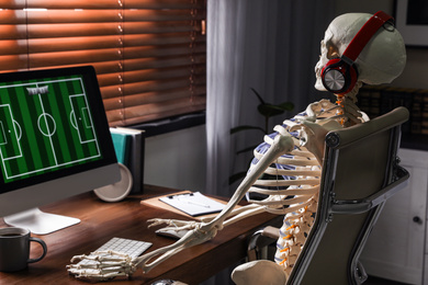 Human skeleton with headphones playing game indoors