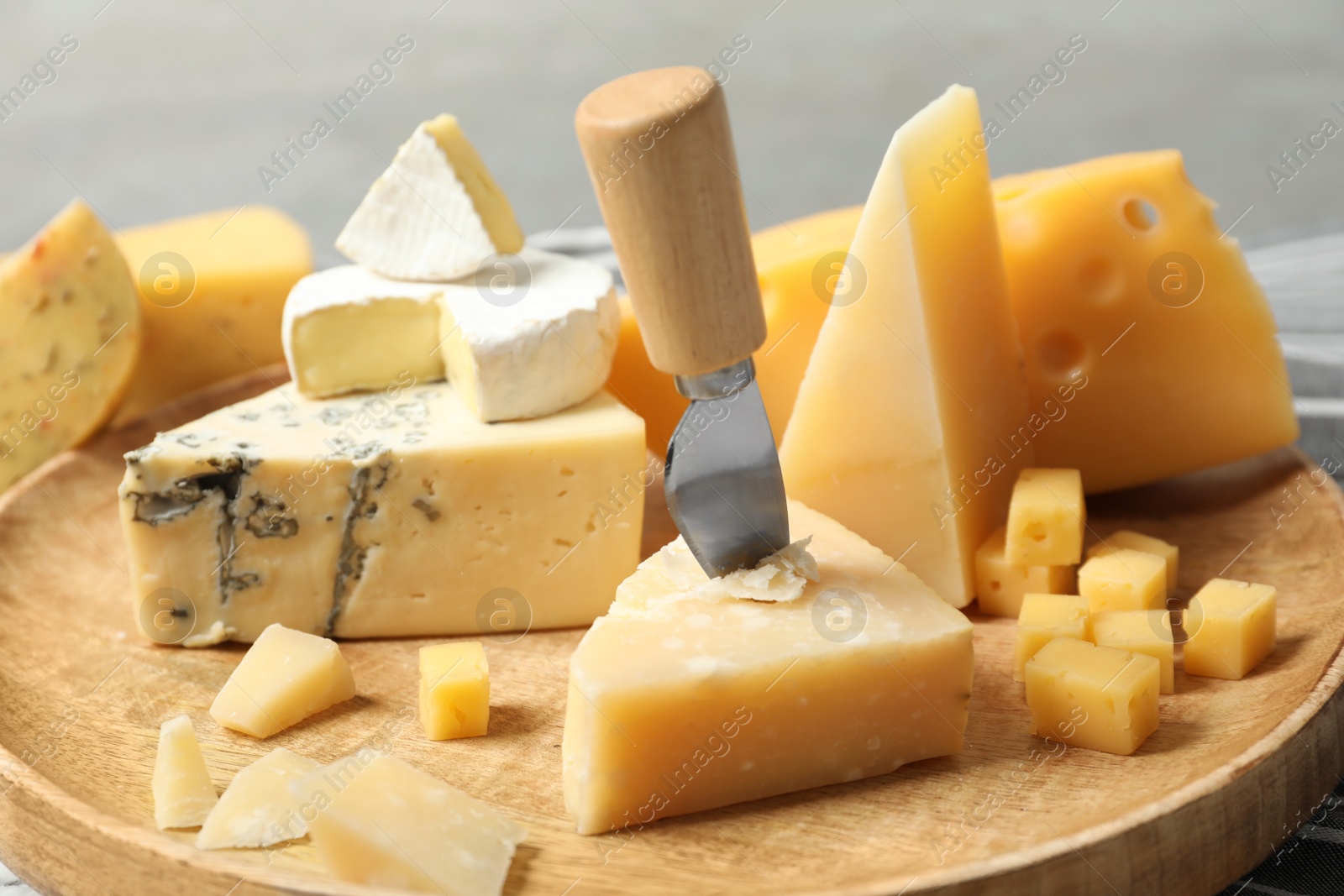 Photo of Different types of delicious cheese in wooden plate, closeup