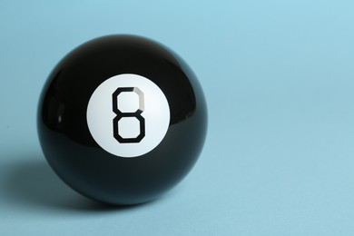 Photo of One magic eight ball on light blue background, space for text