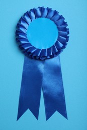 Photo of Blue award ribbon on turquoise background, top view