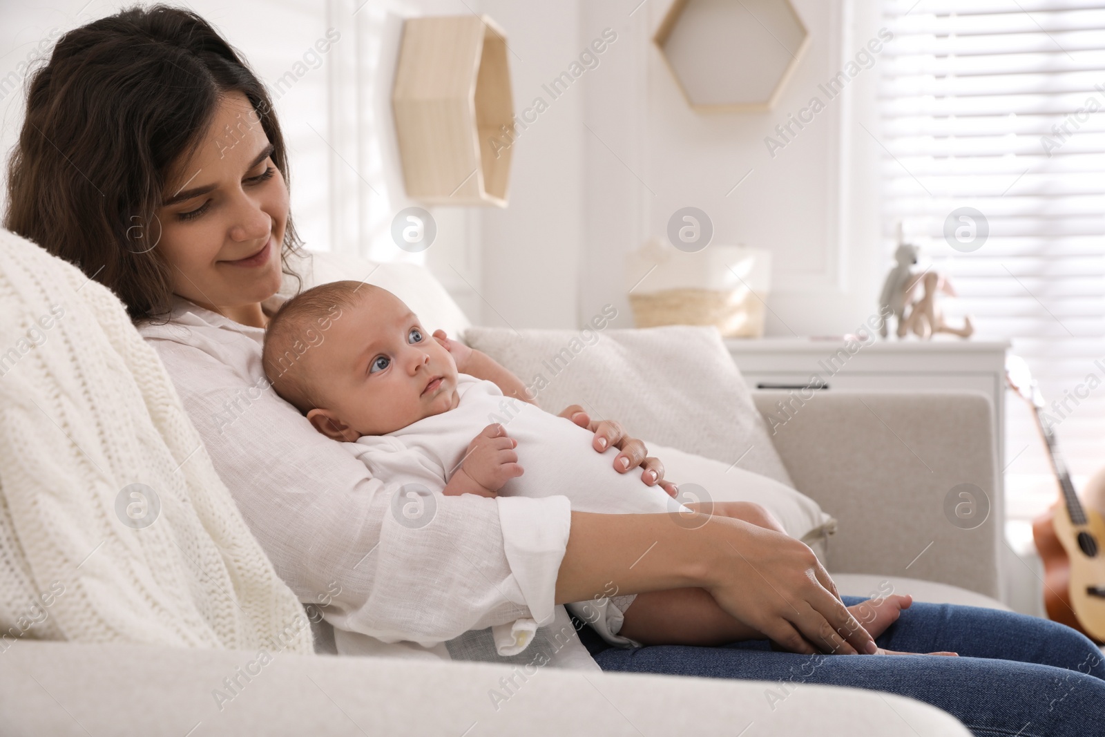 Photo of Happy young mother with her cute baby on sofa at home