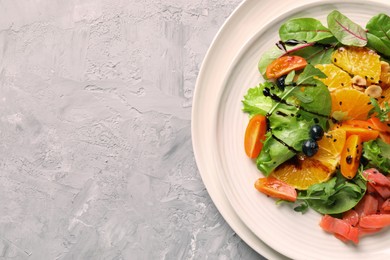 Photo of Delicious salad with salmon on gray textured table, top view. Space for text