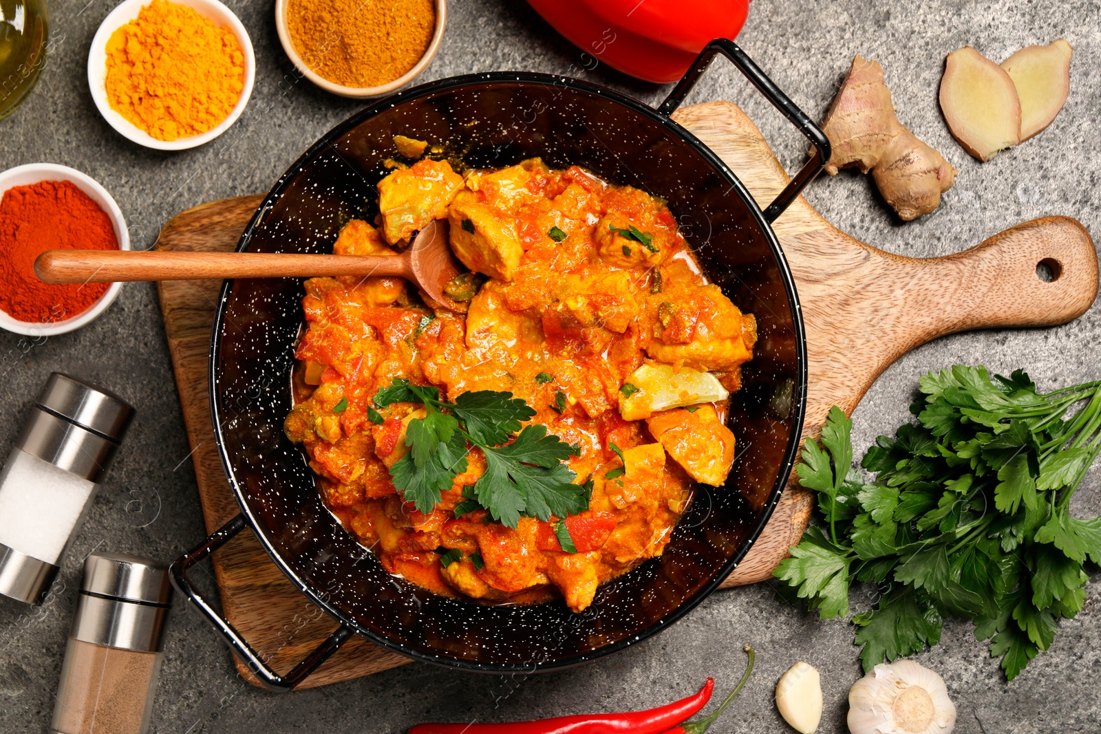 Photo of Delicious chicken curry and ingredients on grey table, flat lay