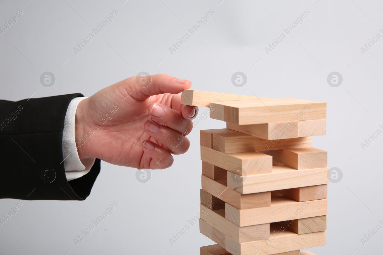 Photo of Woman playing Jenga on light gray background, closeup