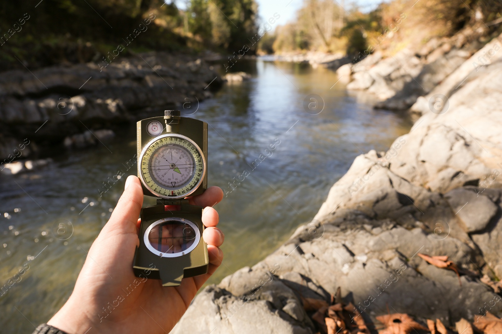 Photo of Man using compass near mountain river, closeup