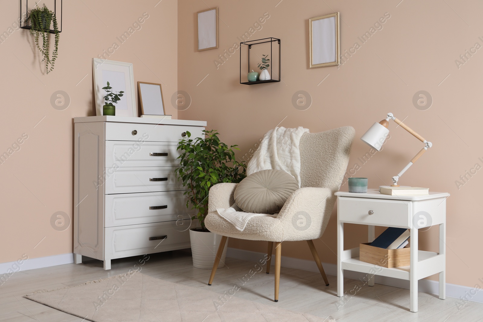 Photo of Cozy room interior with stylish white furniture, desk lamp and beautiful decor elements