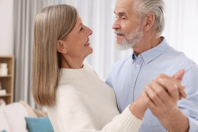 Happy affectionate senior couple dancing at home