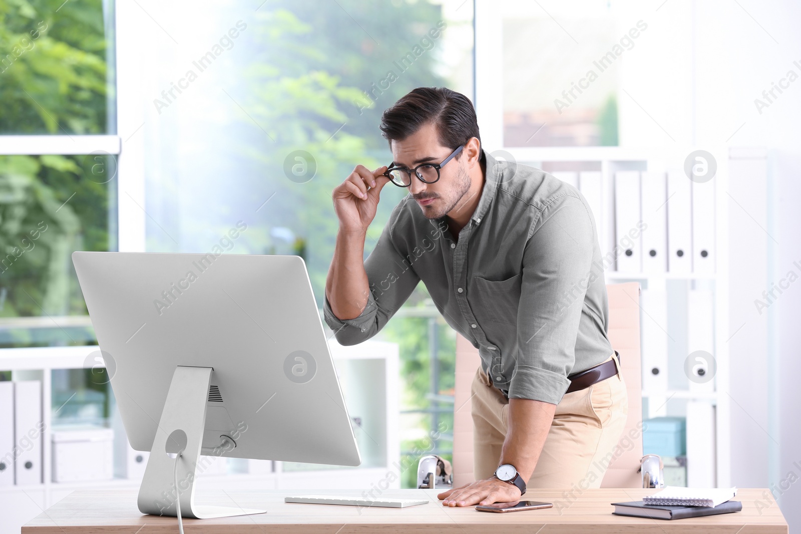 Photo of Handsome young man working with computer in office