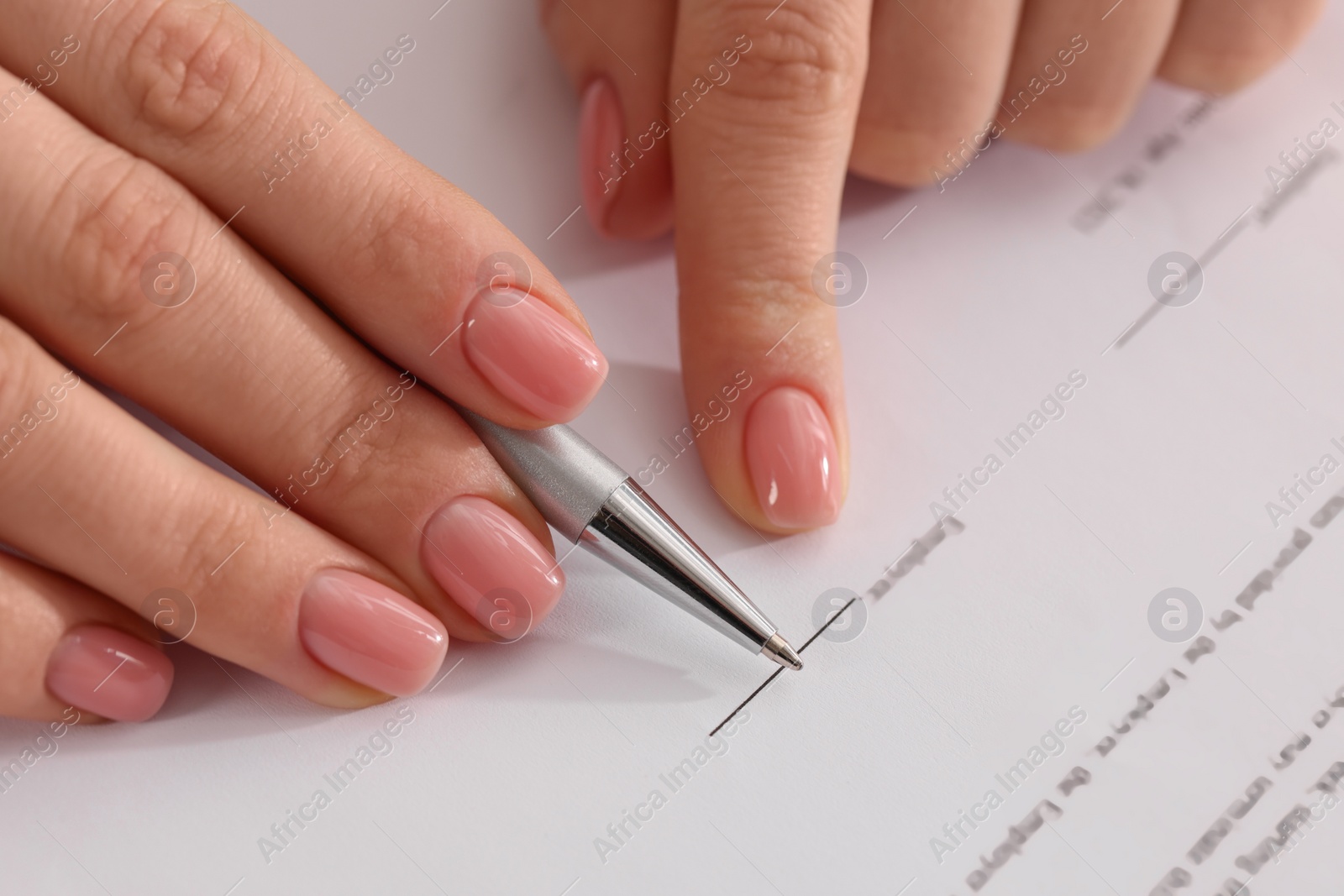 Photo of Woman signing document with pen, closeup view