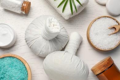 Photo of Flat lay composition of herbal bags and spa products on white wooden table