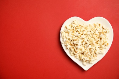 Photo of Plate with tasty fresh popcorn on color background, top view