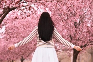 Photo of Young woman in park with blooming trees. Spring look