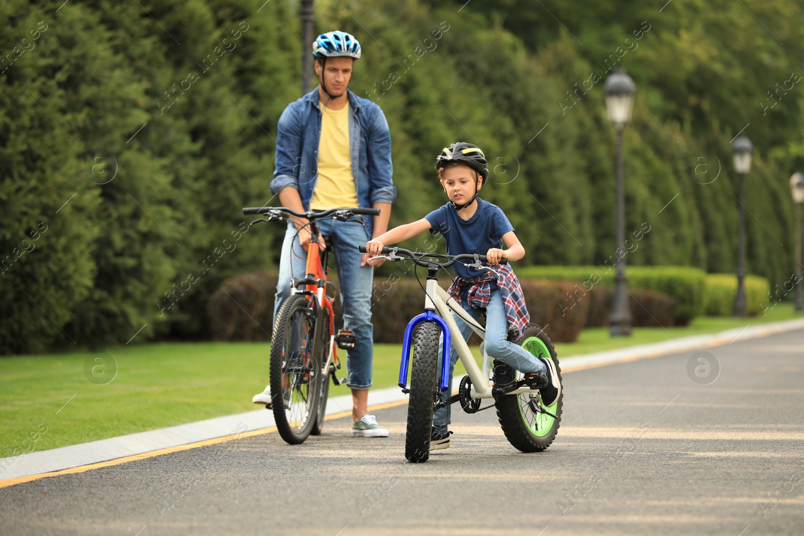 Photo of Dad and son riding modern bicycles outdoors