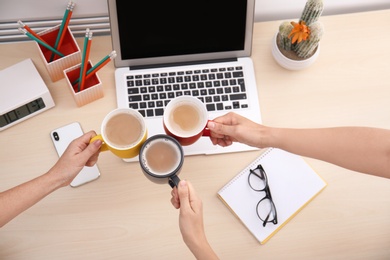 Women holding cups of coffee over table, top view. Break time