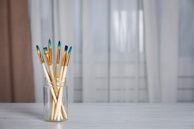 Many different paintbrushes on white wooden table indoors, space for text