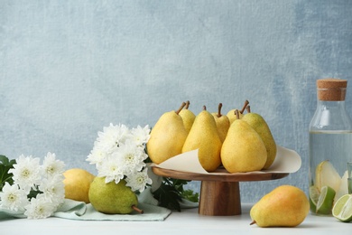 Photo of Stand with fresh ripe pears on table against color background