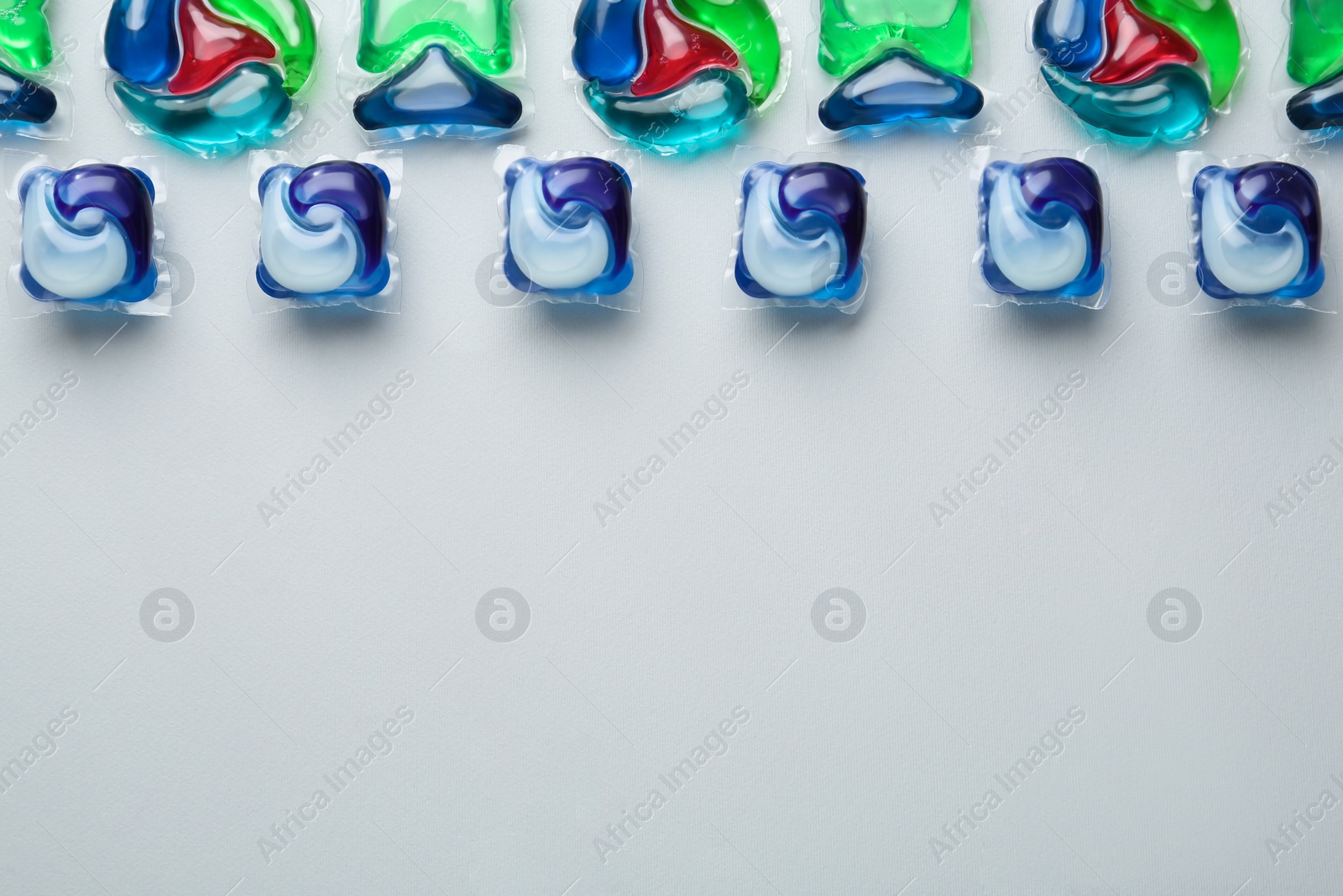 Photo of Laundry capsules on light grey background, flat lay. Space for text