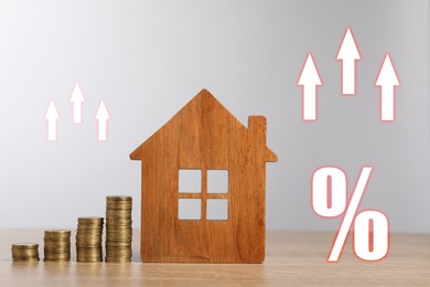 Image of Mortgage rate. Wooden model of house, stacked coins, arrows and percent sign