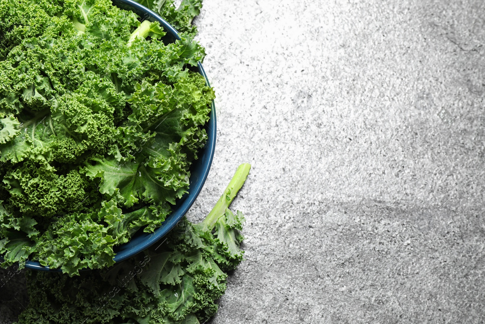 Photo of Fresh kale leaves on grey table, flat lay. Space for text