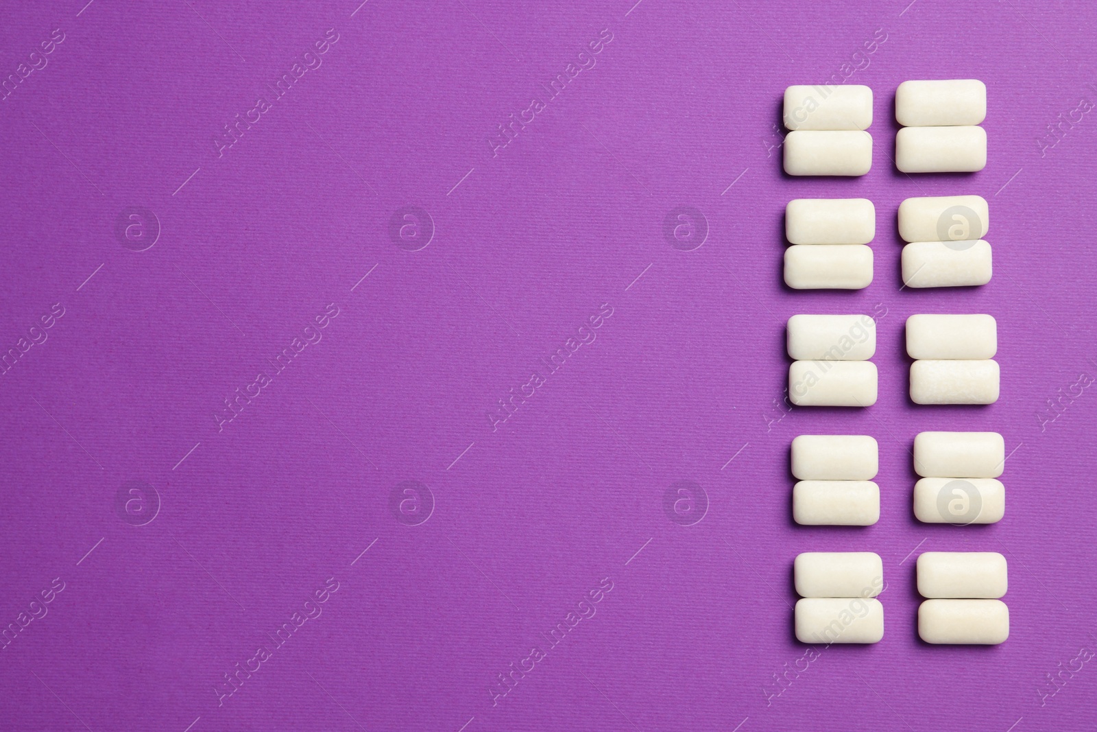 Photo of Tasty white bubble gums on purple background, flat lay. Space for text