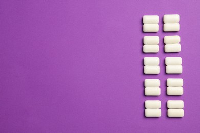 Tasty white bubble gums on purple background, flat lay. Space for text